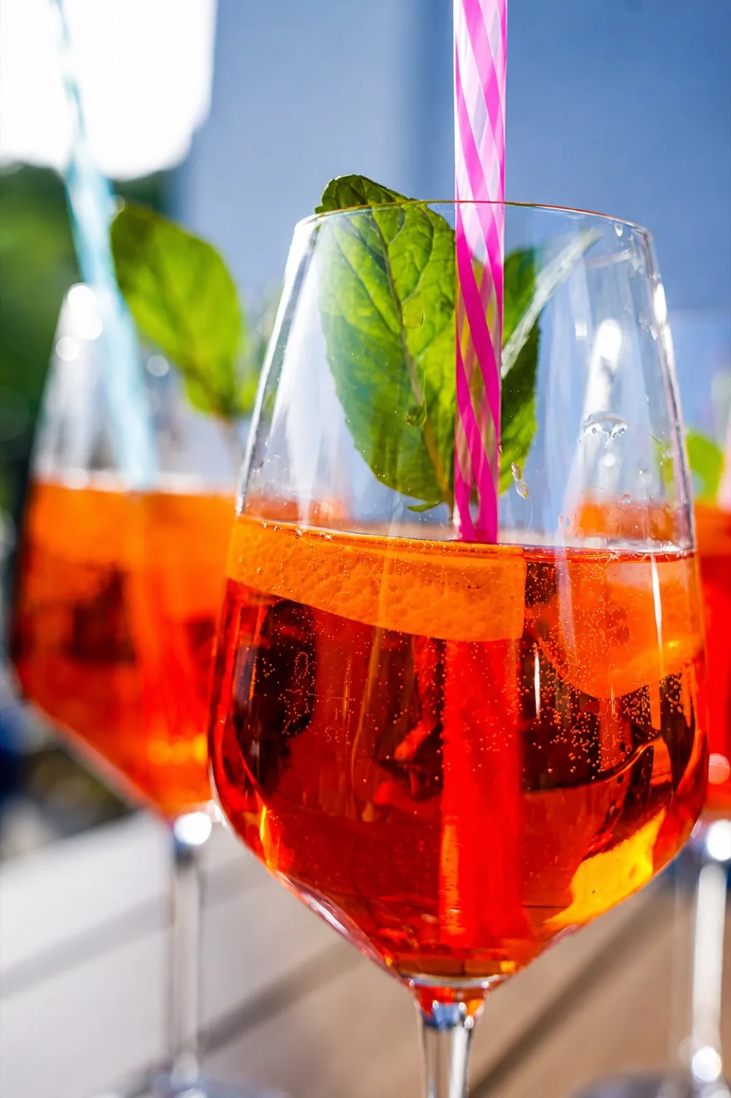Aperol Spritz mit Orangenscheibe und frischer Minze in der Sonne
