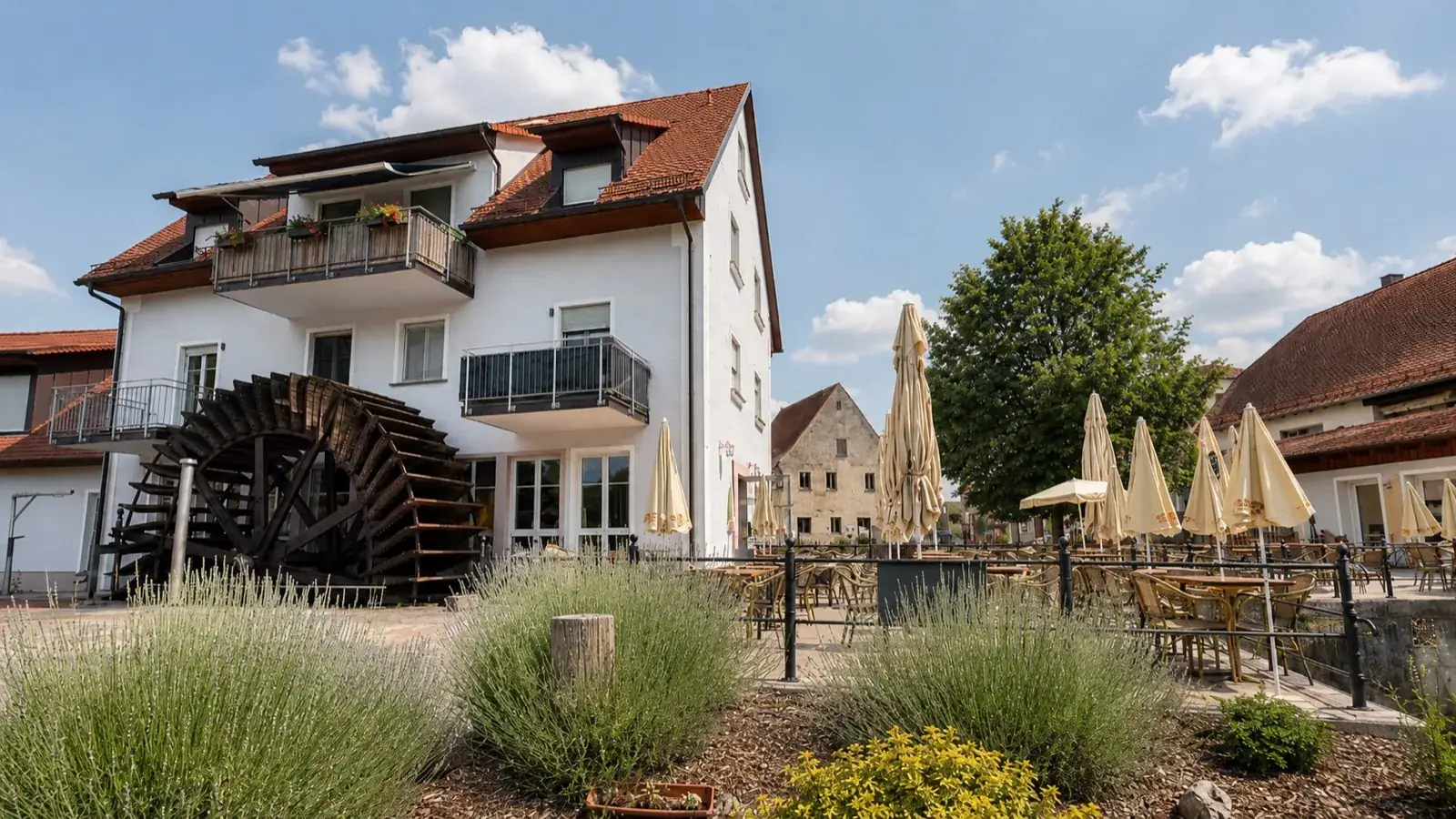 Die alte Mühle von Servus zur Mühle mit Wasserrad, Lavendel und blauem Himmel